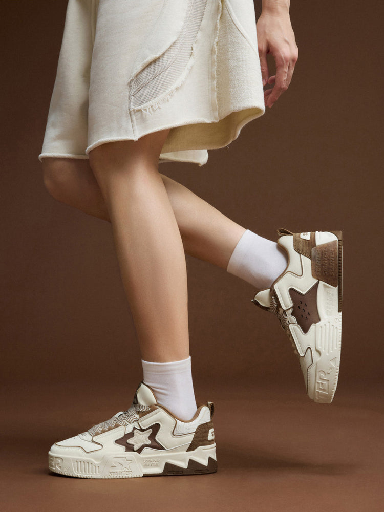STARTER VOL 90S LATTE on-foot side views in a crossed-leg pose, showing the brown inner star panel and cream platform