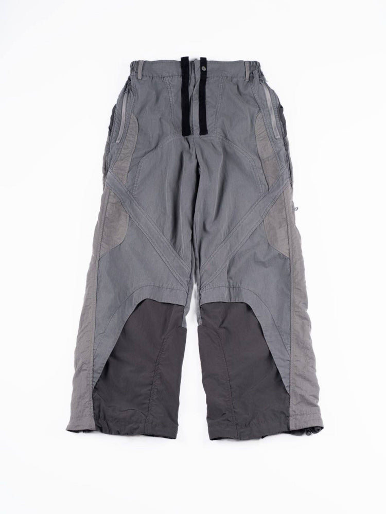 SUPERNOVA alloy gray metallic nylon technical pants — alloy gray front flat-lay showing curved panels and zip pockets