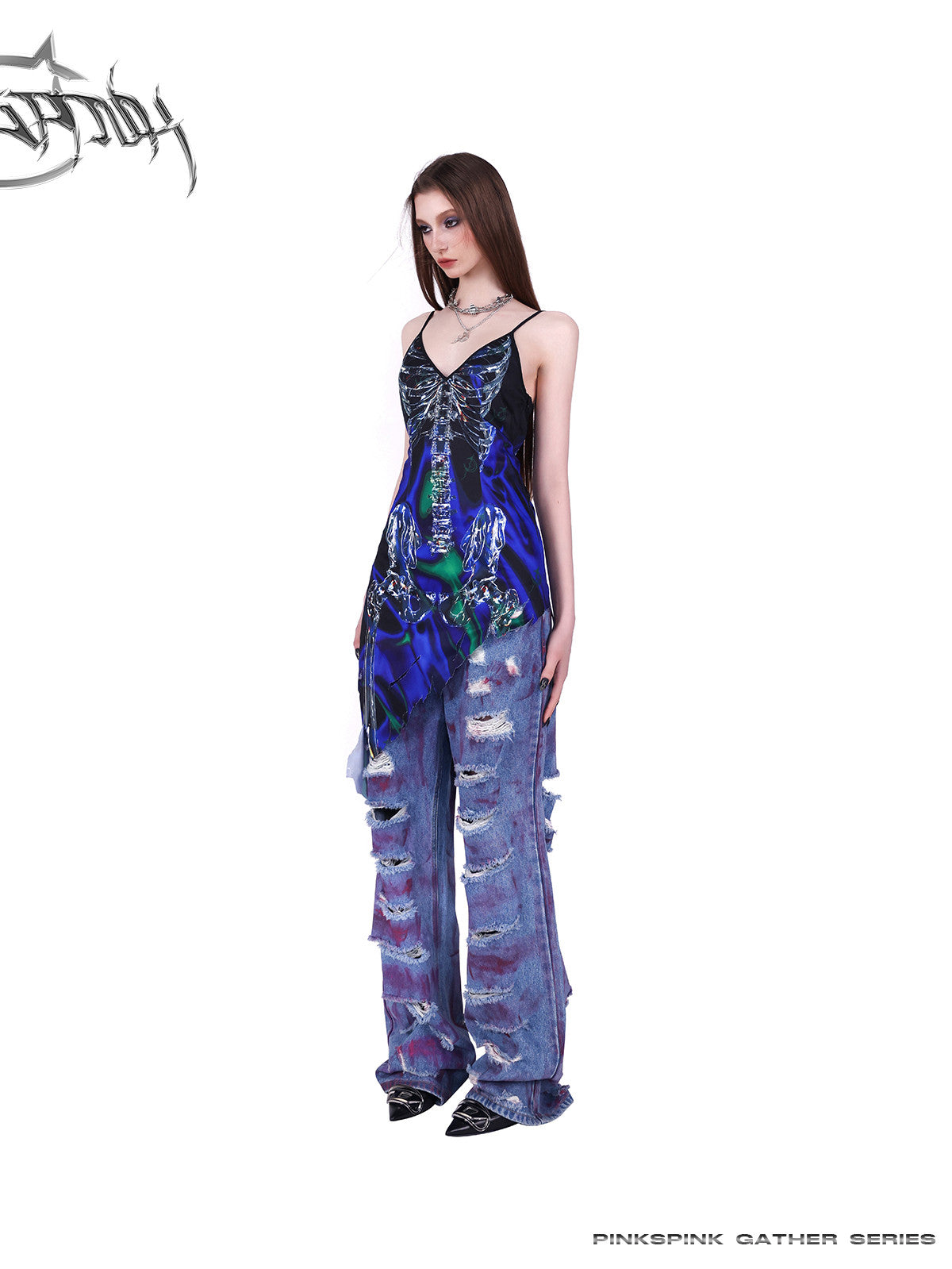PINKSPINK COSMOS skeleton-print asymmetric slip dress in blue green multicolor — angled full-length modeled view layered over jeans