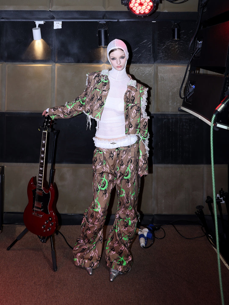 PINKSPINK ELECTRIC MOON distressed camo cropped jacket in CAMOUFLAGE — full-body angled front view beside a guitar.