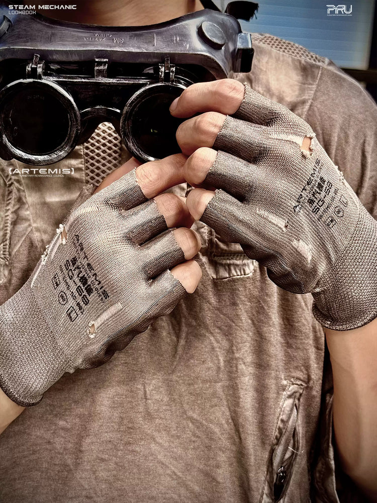 PRECISION CASTING distressed fingerless gloves in brown-gray — modeled close-up holding goggles, showing printed backs and frayed finger openings