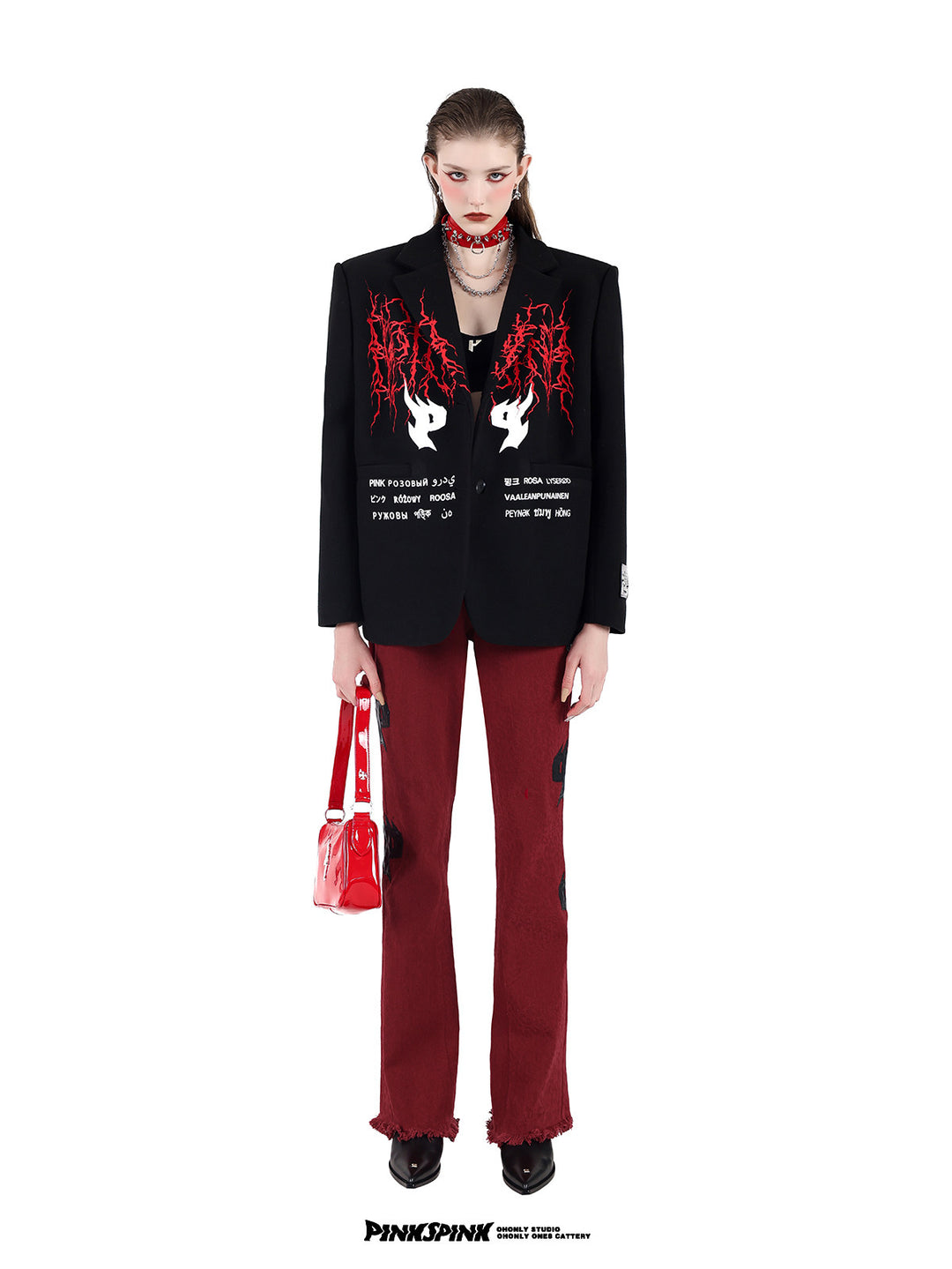 PINKSPINK SPIKE RING studded chain choker in red — full-length front modeled view with a black embroidered blazer and red trousers