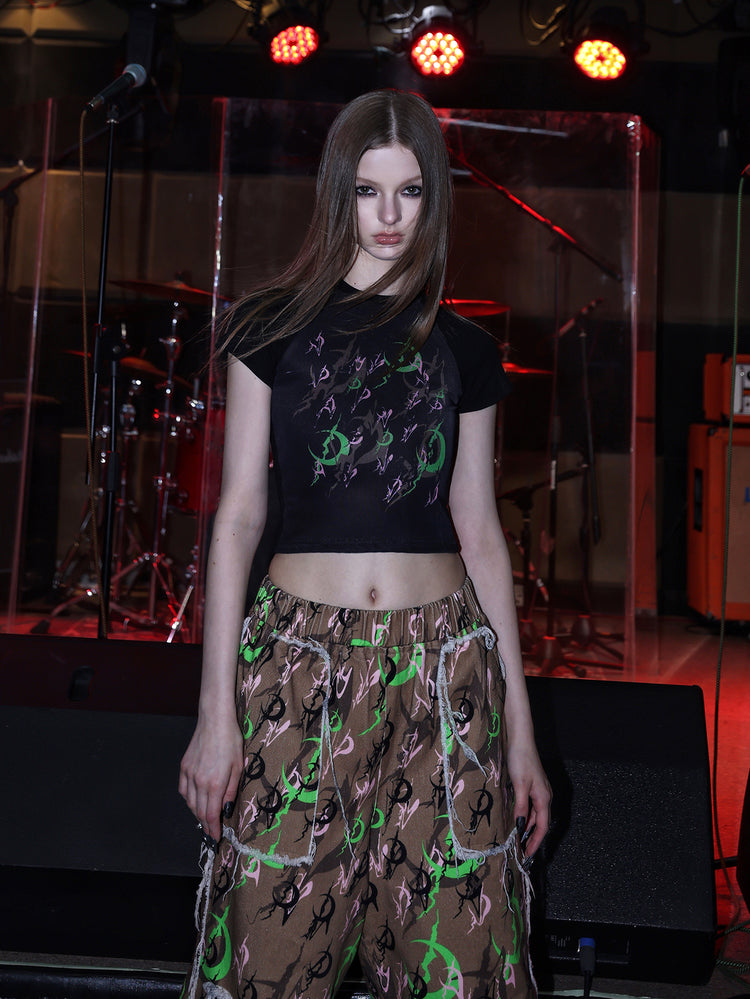 PINKSPINK ELECTRIC MOON distressed camo cropped trousers in CAMOUFLAGE — close front with graphic tee.