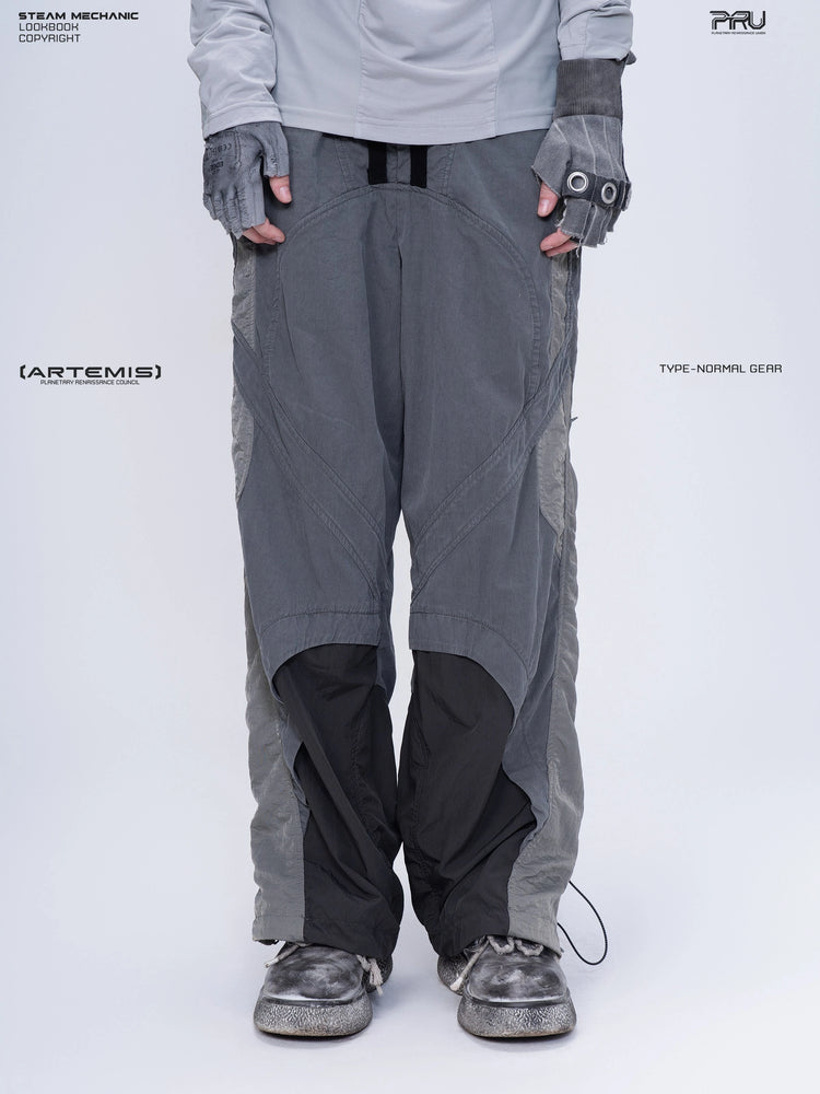 SUPERNOVA alloy gray metallic nylon technical pants — front modeled close-up showing curved panels and hem drawcords