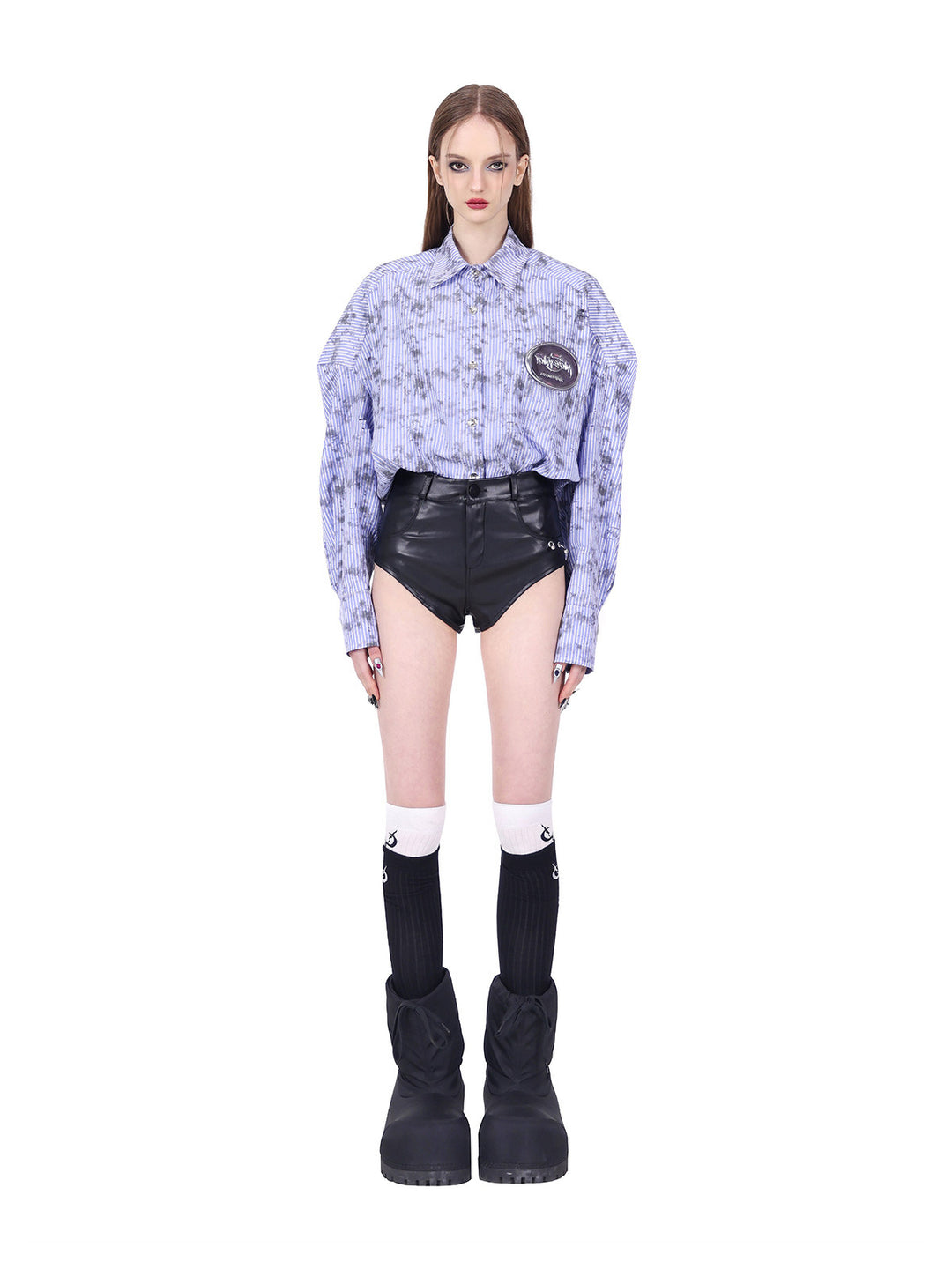 PINKSPINK REBEL ring-pierced faux-leather hotpants in black — front modeled view styled with a tucked striped shirt