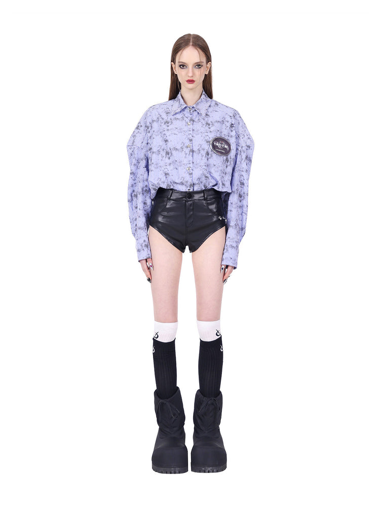 PINKSPINK REBEL ring-pierced faux-leather hotpants in black — front modeled view styled with a tucked striped shirt