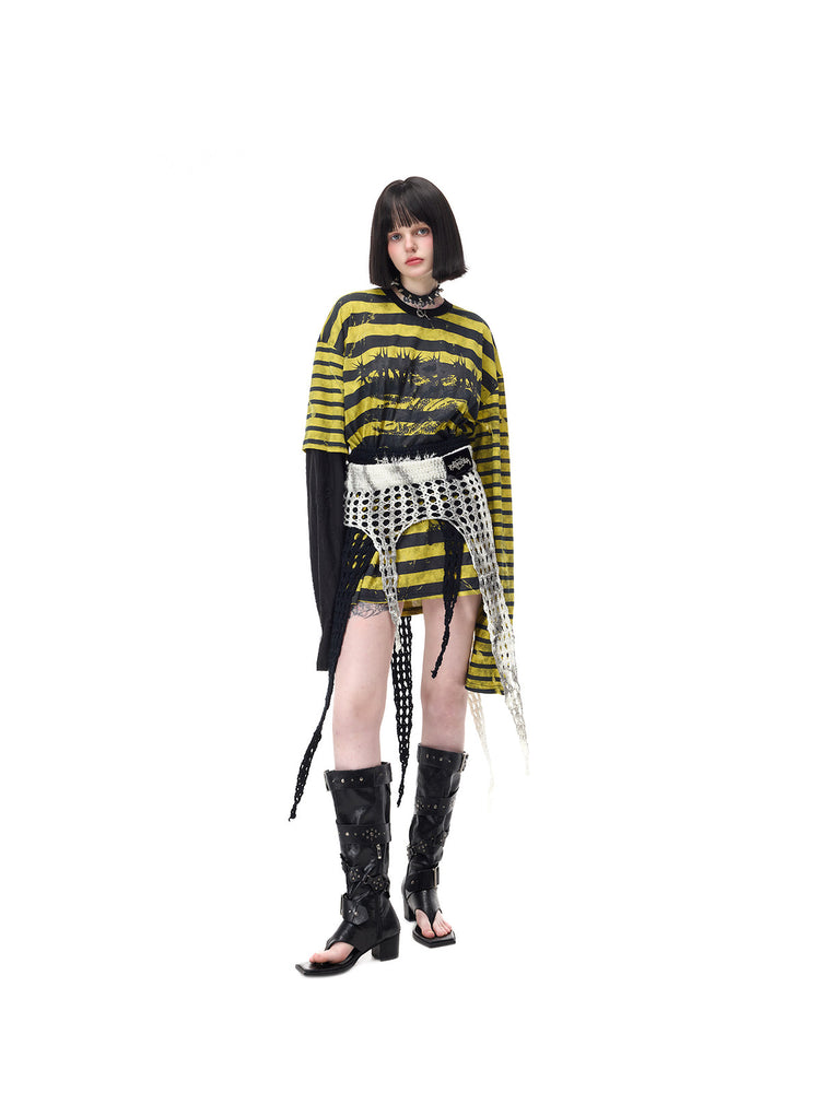 PINKSPINK STATIC asymmetric striped burnout long-sleeve tee in black and yellow — three-quarter front modeled view with the tee tucked beneath a separate white open-knit waist layer