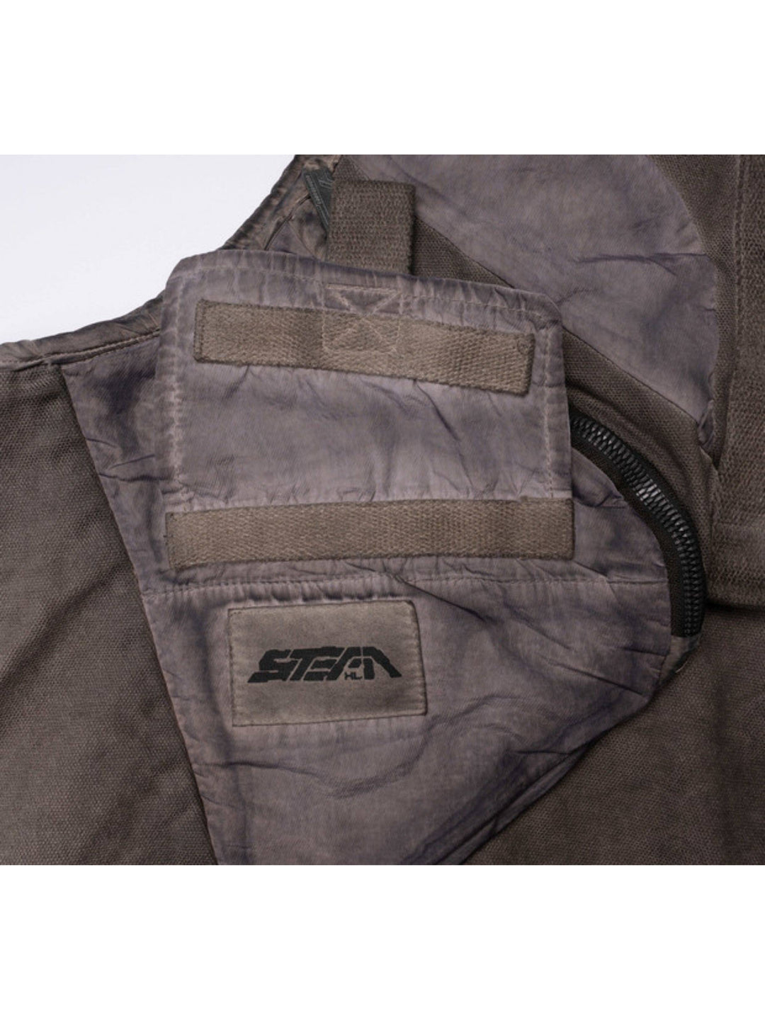 FISSION modular vest in mercury brown — close-up of the utility pocket, webbing and logo patch