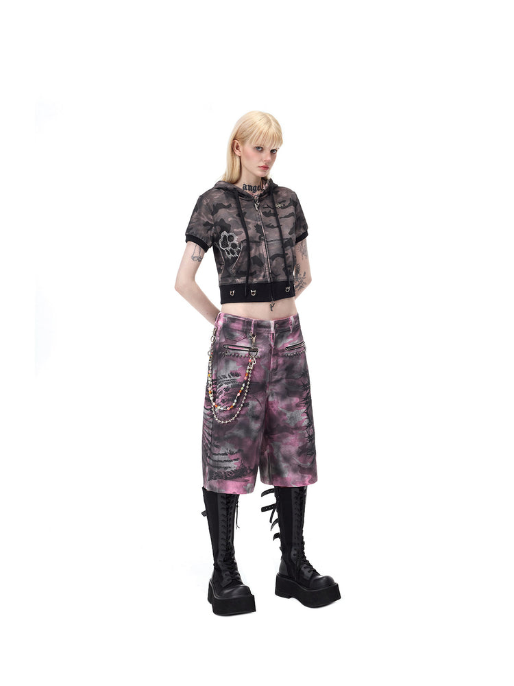 PINKSPINK ELECTRIC MOON coated camouflage denim shorts in pink-gray camouflage — full angled front view with hands behind the back