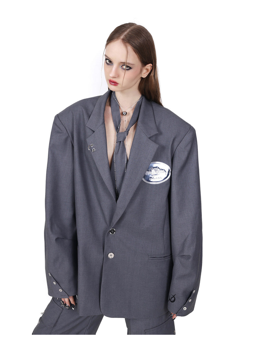 PINKSPINK REBEL pierced oversized tailored blazer in gray — close front modeled view showing sculpted shoulders and metallic-look chest emblem