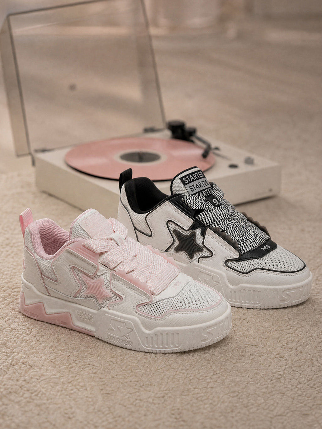Pink and black-and-white STARTER VOL 90S sneakers beside a record player, front three-quarter view