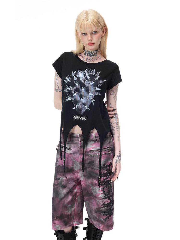 PINKSPINK PUNK CACTUS studded pointed-hem tee in black — three-quarter front modeled view with arms behind the back, also shown in the hero collage