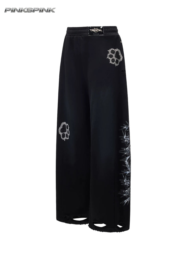 PINKSPINK CATPAW rhinestone curved-leg sweatpants in black — isolated front garment view showing curved legs, rhinestone paws and distressed hems