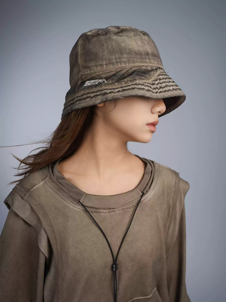 PIONEER mercury brown distressed nylon bucket hat — modeled close-up showing the washed finish and embroidered STEAM logo