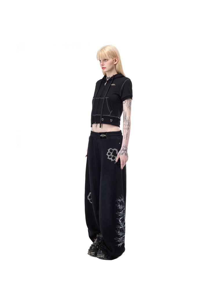 PINKSPINK CATPAW rhinestone curved-leg sweatpants in black — full-length side modeled view showing the curved silhouette and thorn print