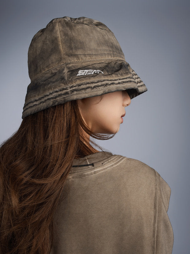 PIONEER distressed nylon bucket hat — mercury brown over-shoulder modeled view showing the logo