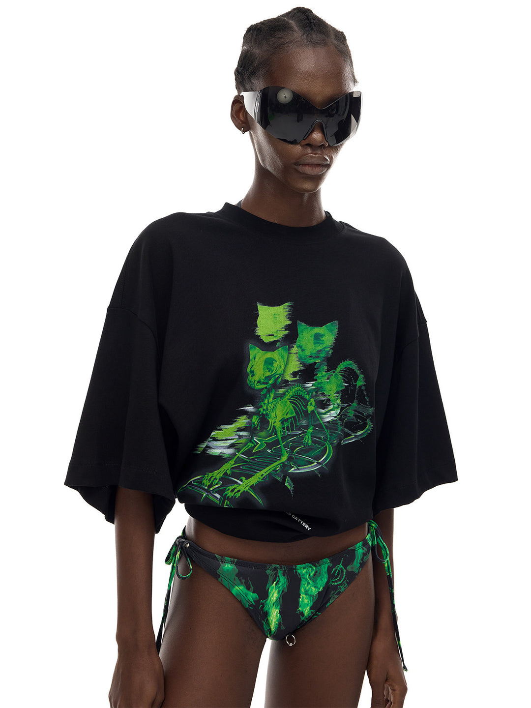 PINKSPINK MONSTER cat-skeleton oversized graphic tee in black — close front modeled view showing the graphic with the hem rolled up