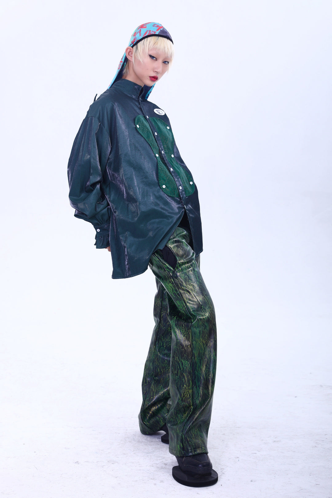 EMBRYO TRIANGLE ARMOR lace-inset leather pants in green — side-front modeled outfit showing the straight-leg silhouette