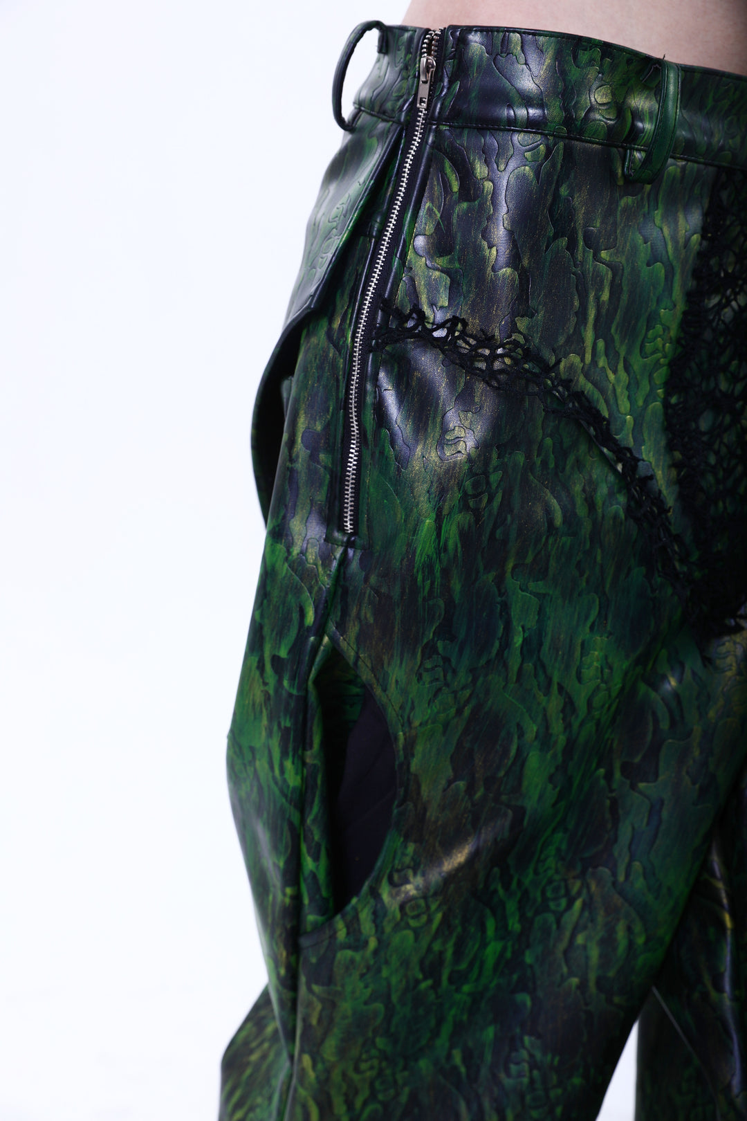 EMBRYO TRIANGLE ARMOR lace-inset leather pants in green — angled hip close-up showing the side zipper and curved pocket