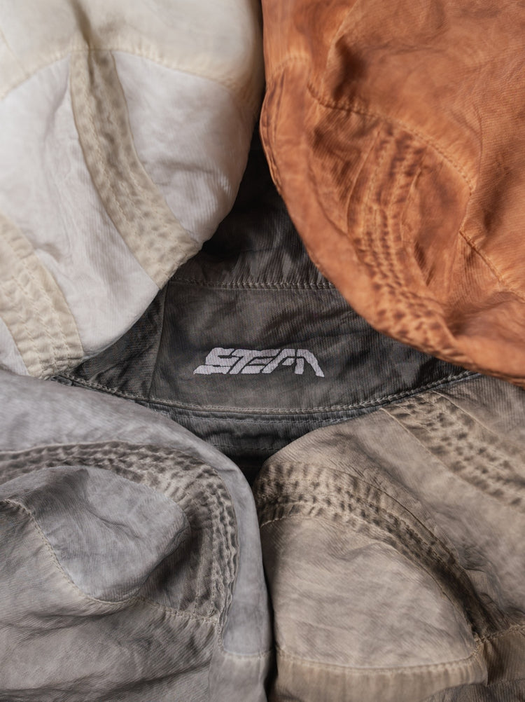 PIONEER distressed nylon bucket hat — close-up of washed nylon texture and printed logo across the hat colors