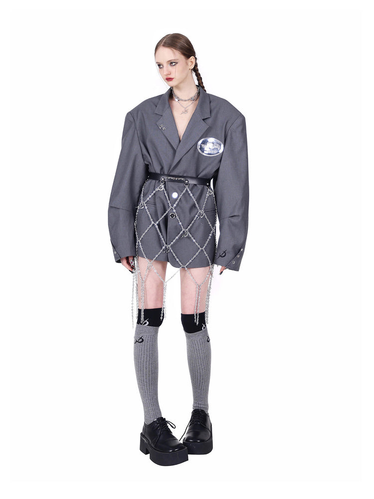 PINKSPINK REBEL pierced oversized tailored blazer in gray — angled front view styled with a chain belt and knee-high socks