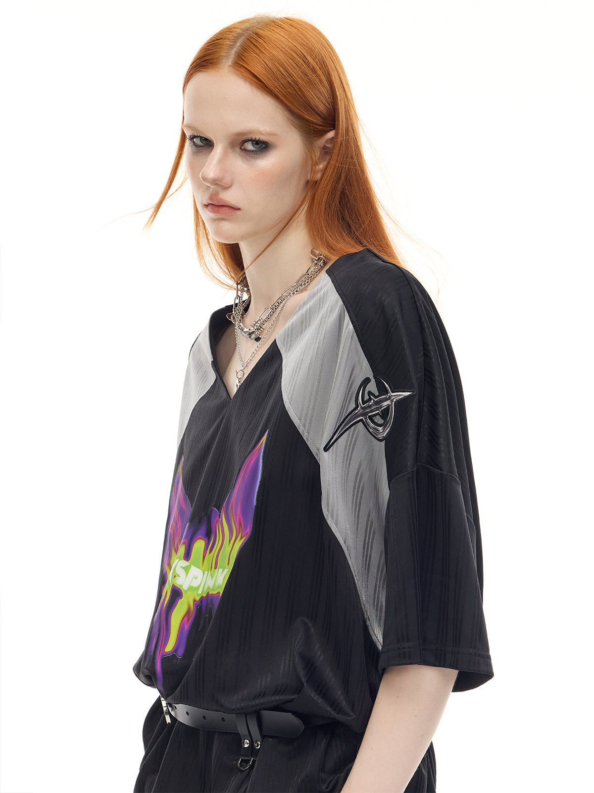 PINKSPINK FLAMECAT oversized sports jersey in black and gray — close angled view of the embroidered shoulder emblem and V-neck