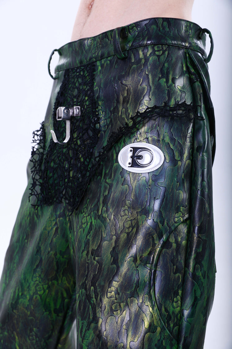 EMBRYO TRIANGLE ARMOR lace-inset leather pants in green — front waist close-up showing black lace inserts, metal clasp and oval logo plaque