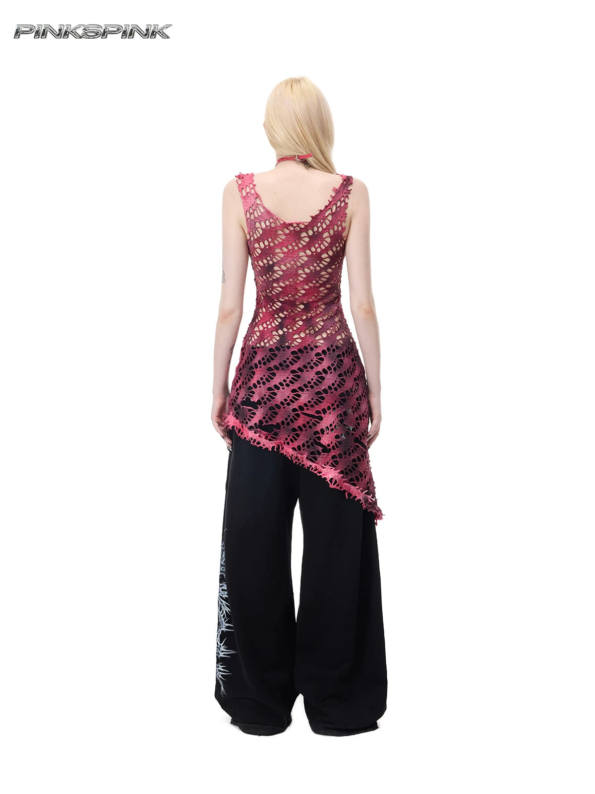 PINKSPINK AFTERGLOW distressed open-knit asymmetric dress in hot pink — full-length rear modeled view showing the asymmetric hem over separate black trousers