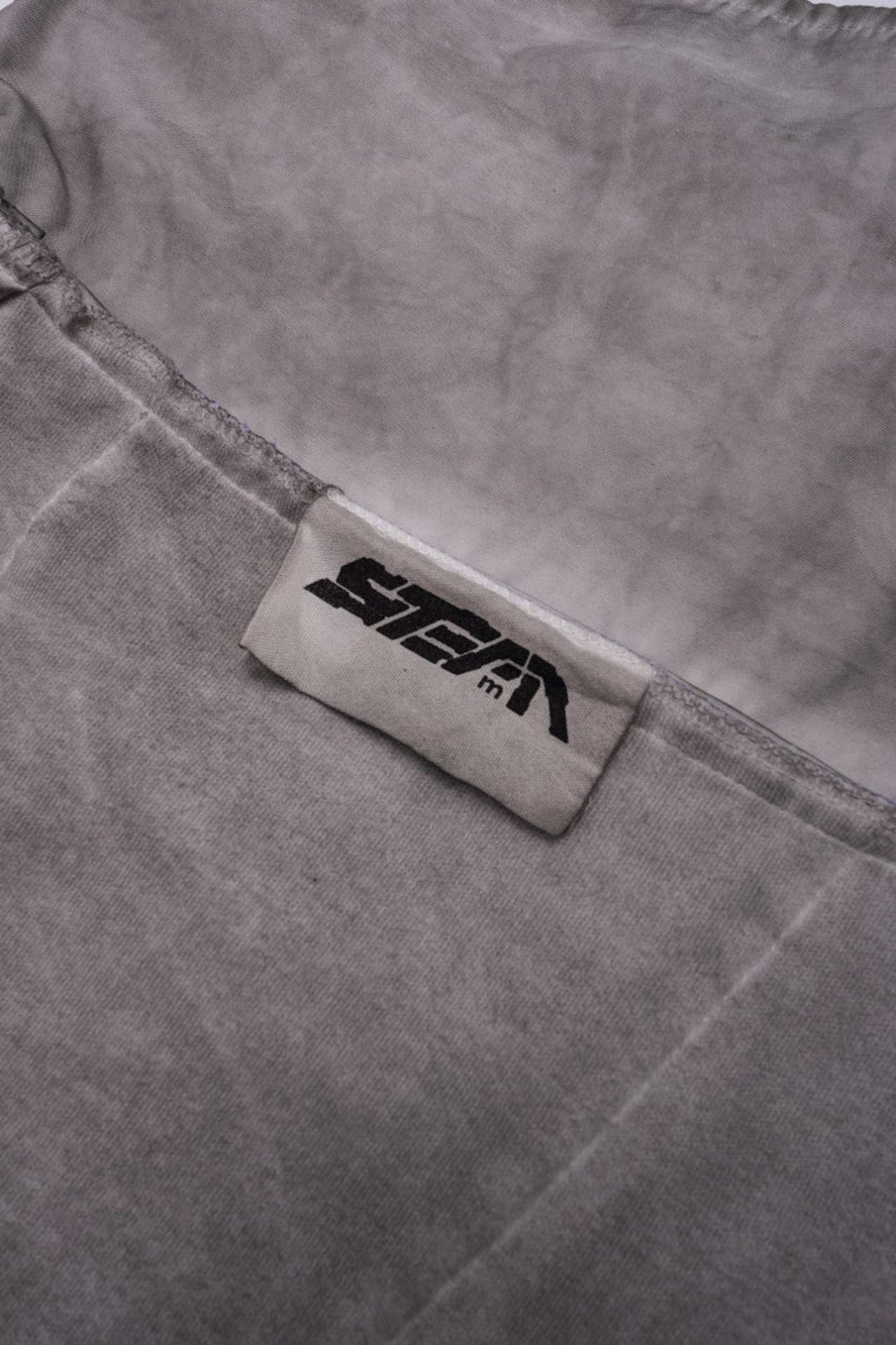 PIONEER eris white detachable-pocket utility hoodie — close-up of the sewn STEAM brand label