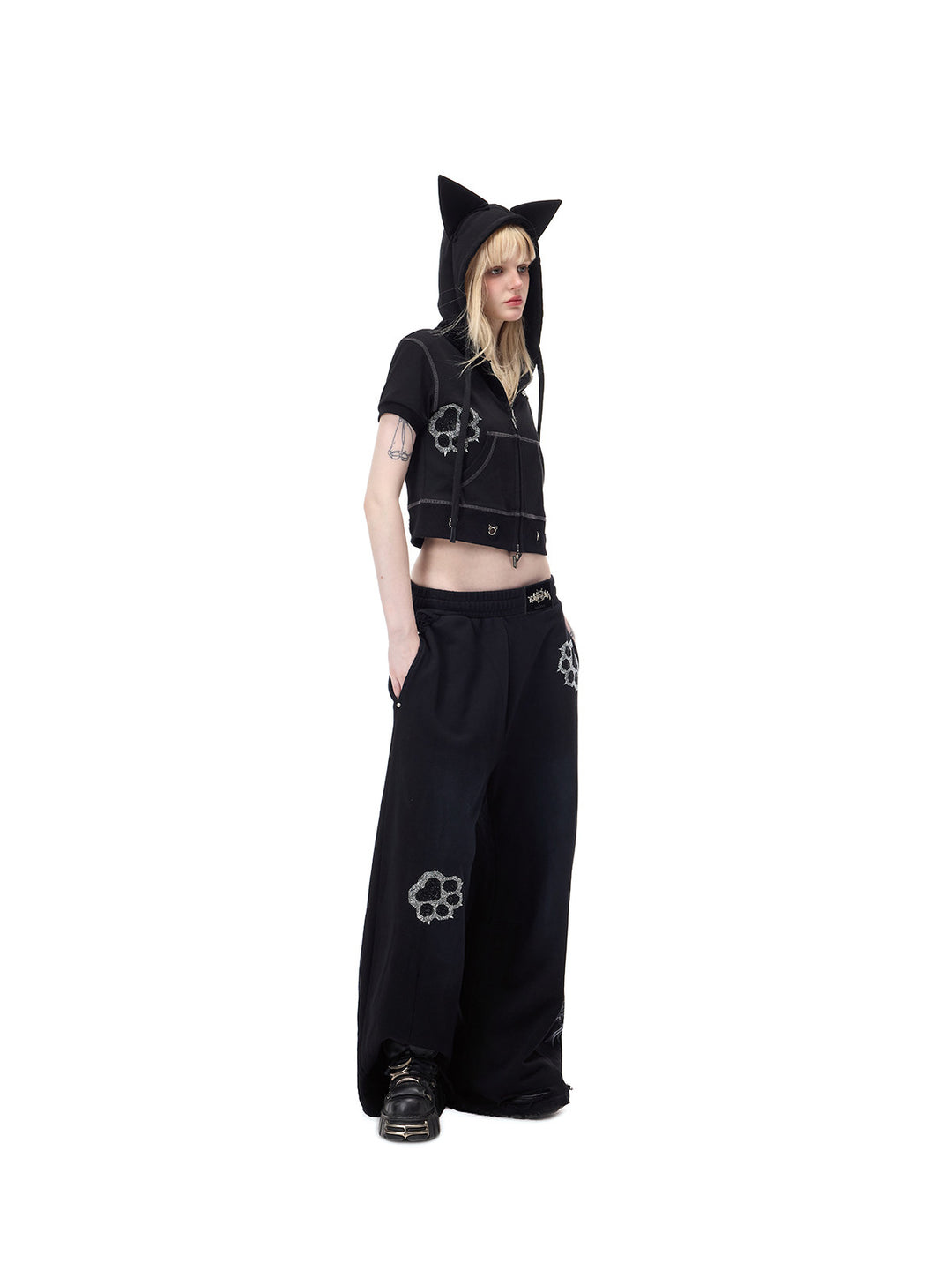PINKSPINK CATPAW rhinestone curved-leg sweatpants in black — angled full-length front modeled view showing the roomy leg shape
