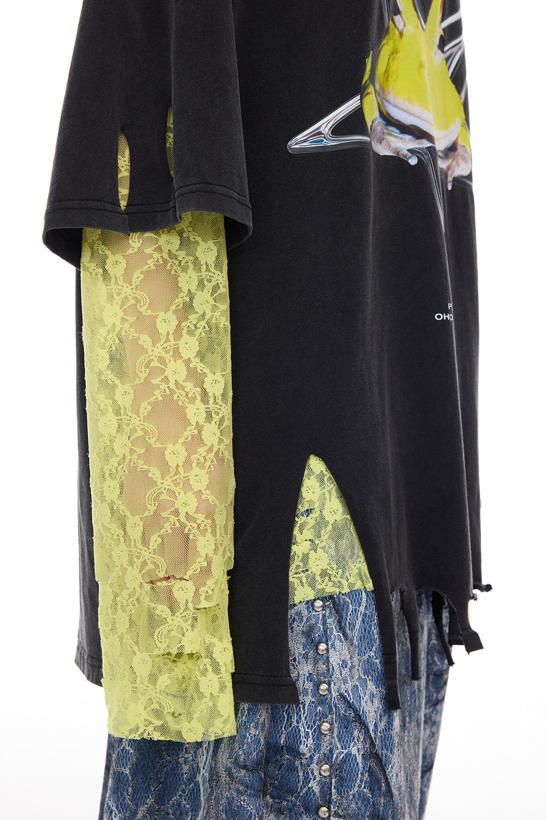 PINKSPINK HORNED FROG distressed graphic tee in black — close-up of the distressed hem and side opening, styled over a separate yellow lace layer