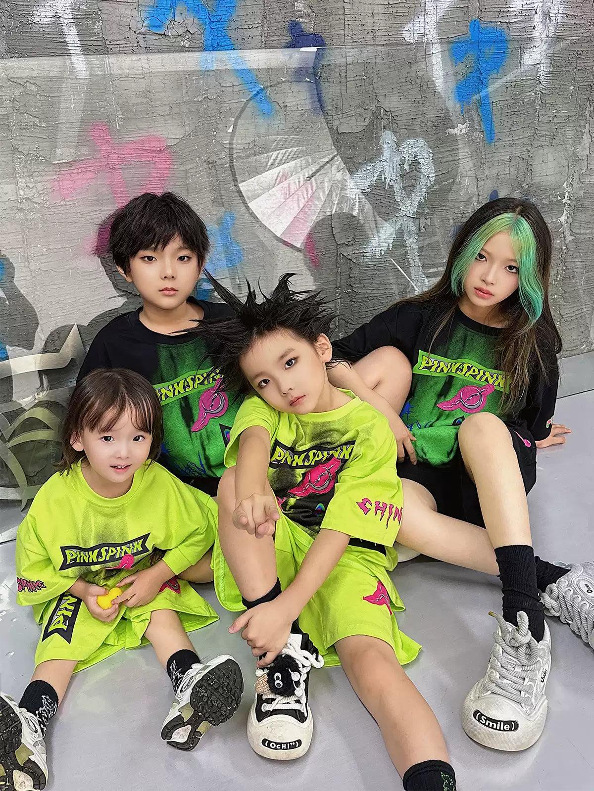 PINKSPINK COLLISION kids graffiti tee and shorts set — seated group modeled view showing both colorways