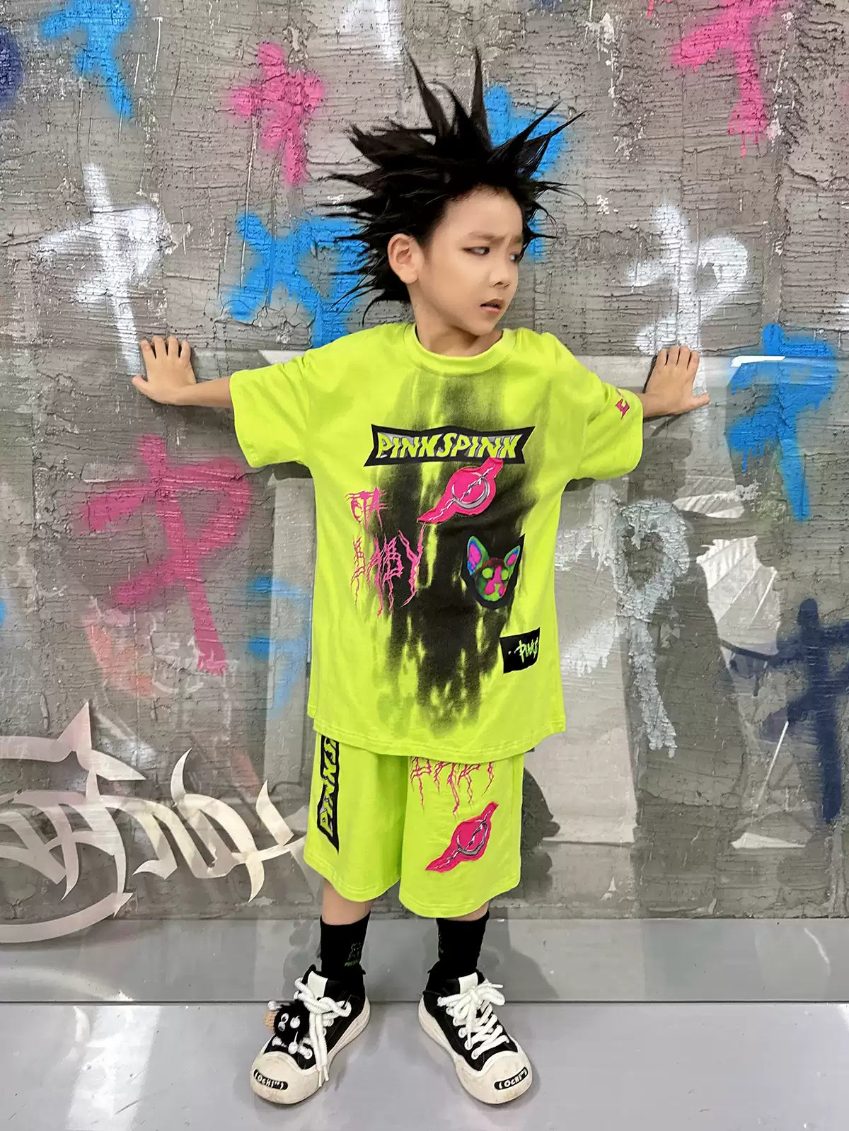 PINKSPINK COLLISION kids graffiti tee and shorts set — neon-green modeled front view with arms extended