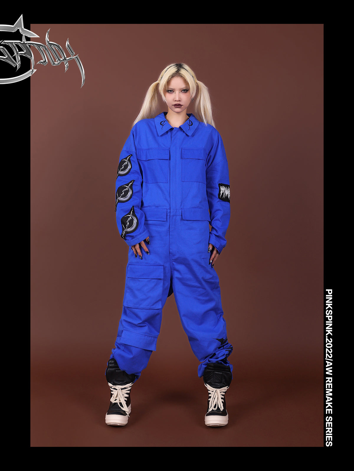 Front view of the blue REMAKE jumpsuit with hands beside the thigh pocket