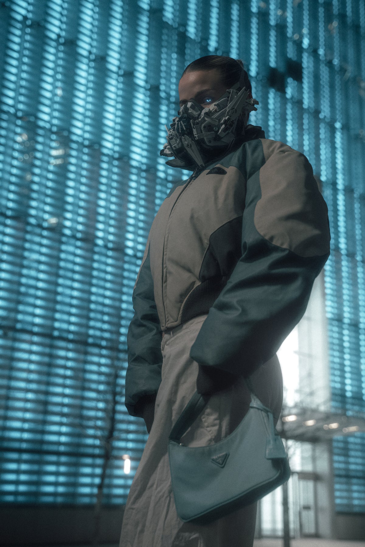 Masked futurewear figure in a luminous city interior