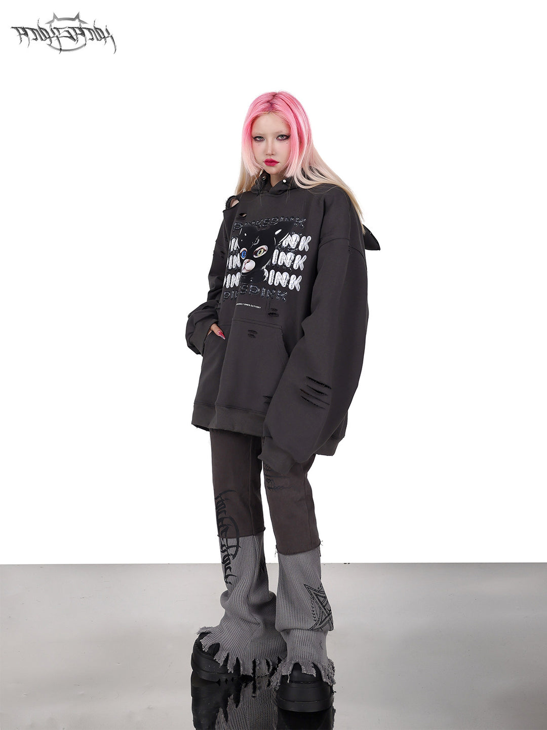 PINKSPINK DEVON CAT distressed mask hoodie in gray — front modeled view with a relaxed sideways lean and gray trousers