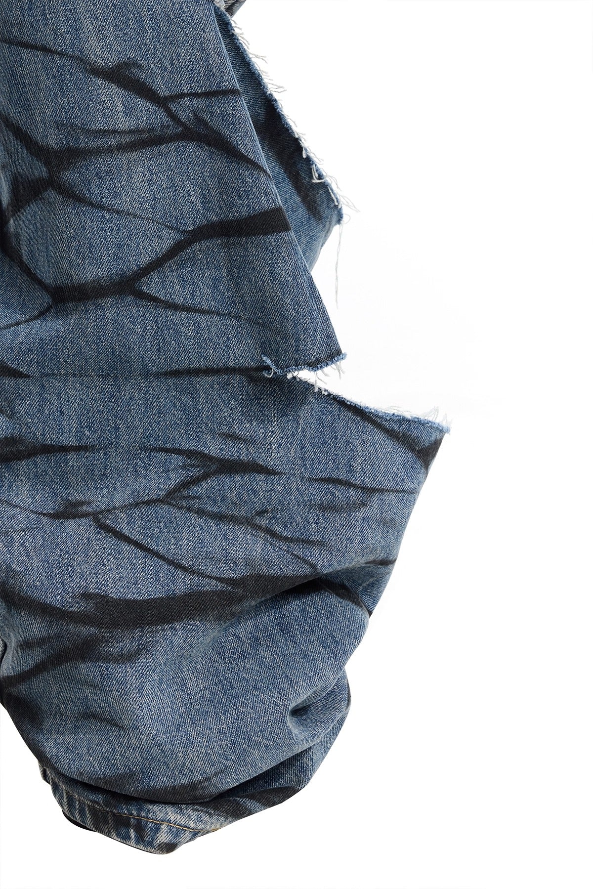 PINKSPINK REMAKE layered graffiti low-rise jeans in washed blue denim — close-up of a wide hem, frayed panel edge and hand-sprayed black marks.