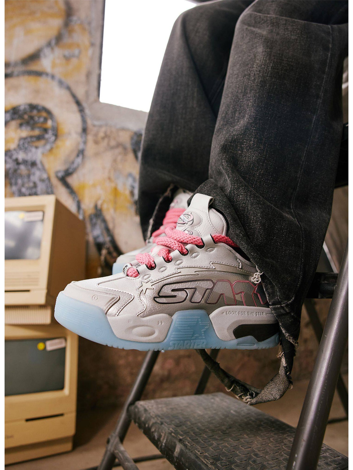 Close-up of silver-blue STARTER platform sneaker with pink laces worn with dark jeans