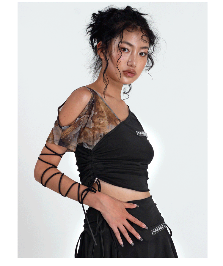 4RE1GN TIE-DYE SLEEVE asymmetric crop top, side-front pose with the tied arm raised