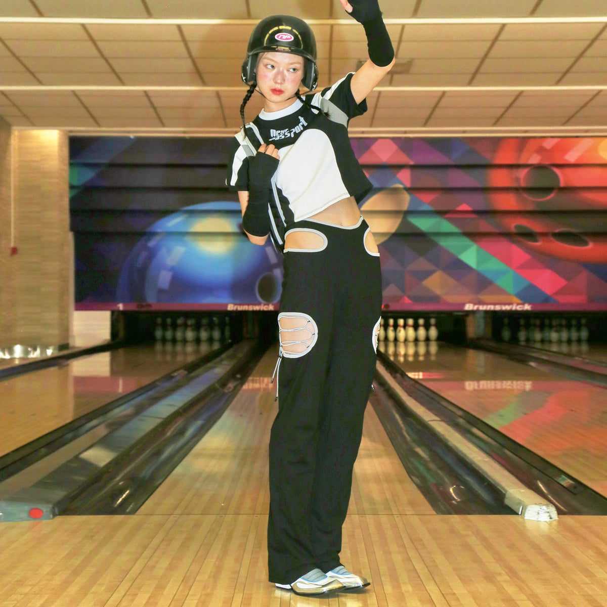 NEXT PASSPORT RETROFUTURE cutout pants, bowling-lane standing outfit with green headwear