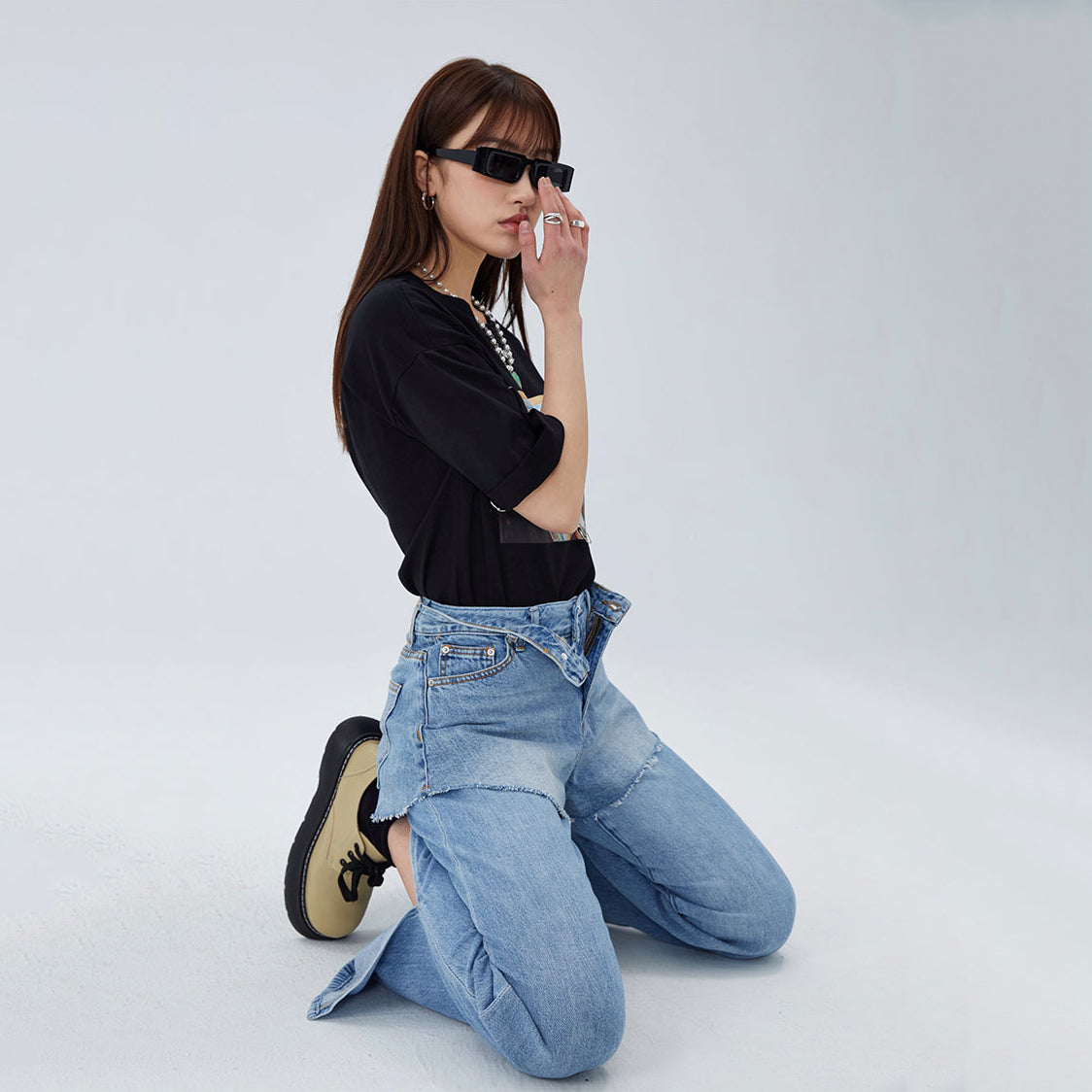 CLICK CHIC HACKWRENCH layered denim shorts, kneeling pose with a hand near the face over separate jeans